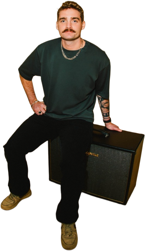 Liam Dever, seated on a guitar amplifier.